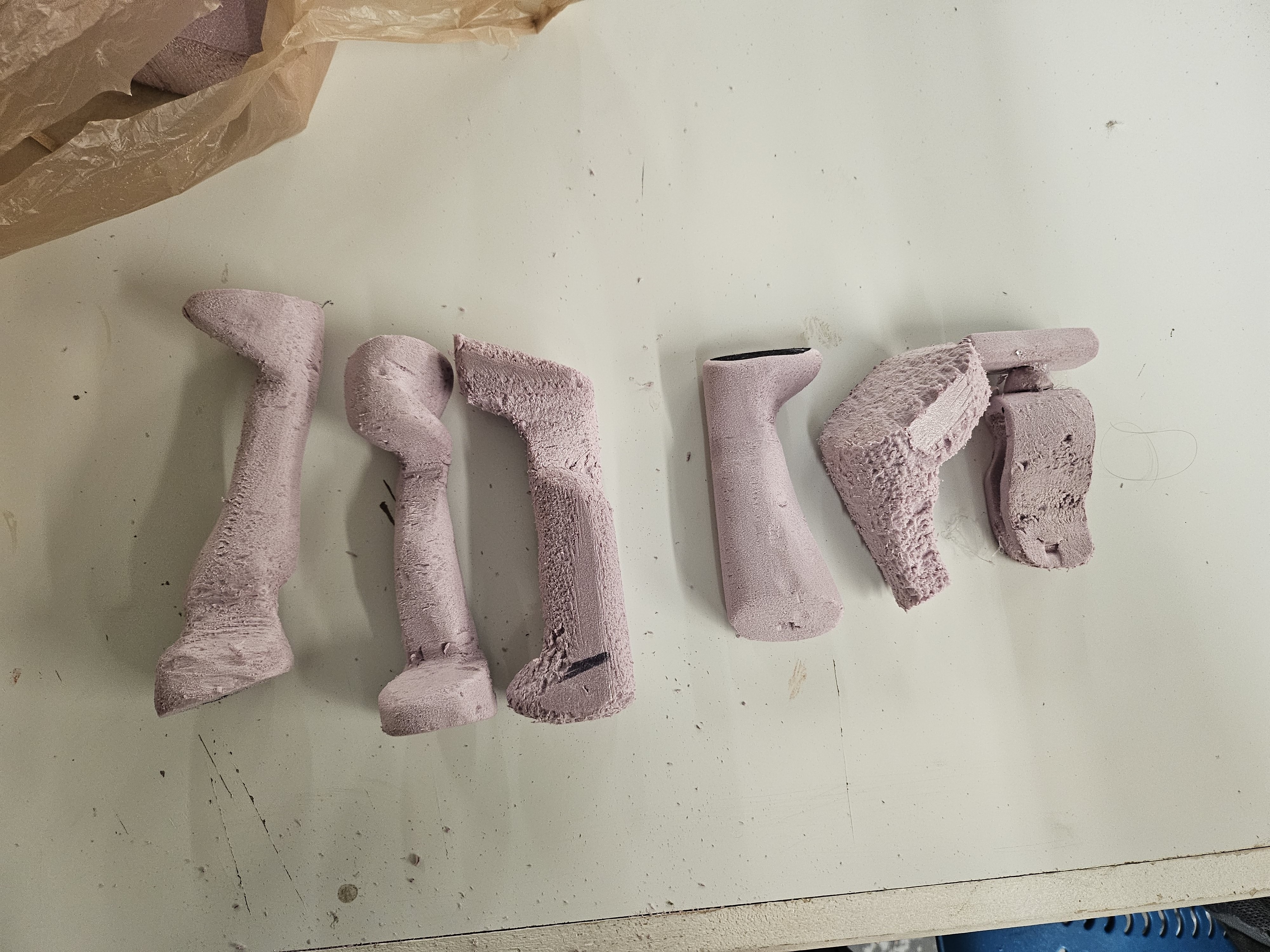 DONE. concept foam cuts — four rough pink foam handle directions laid out before refining